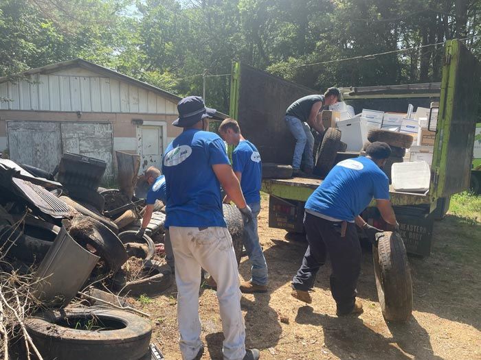 A group of men in blue shirts are loading tires into a truck