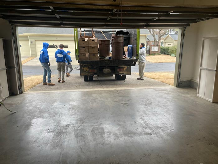 A group of men are standing in a garage next to a moving truck.