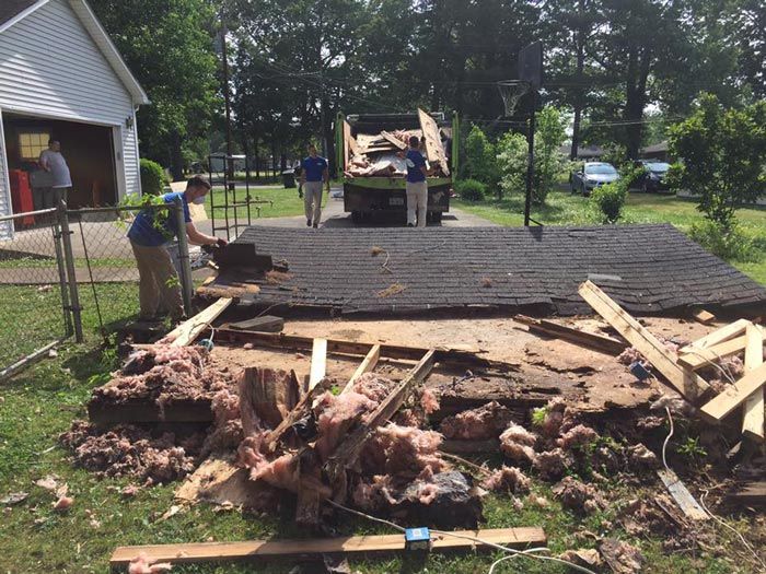 A group of people are working on a roof of a house.