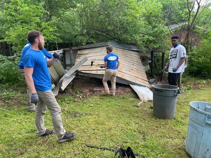 A group of people are working on a roof of a house.