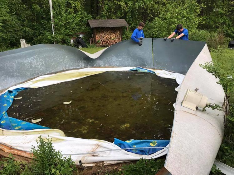 Two men are working on an empty swimming pool.