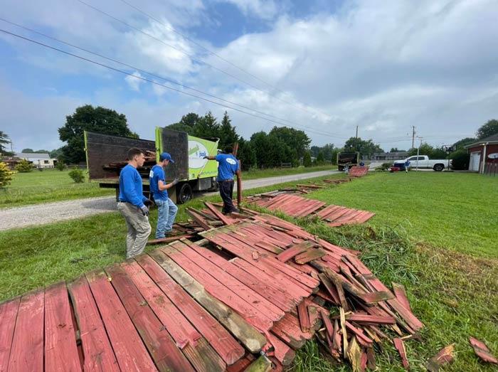 A group of men are standing next to a pile of wood.