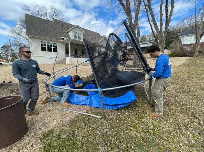 A group of men are working on a trampoline in front of a house.