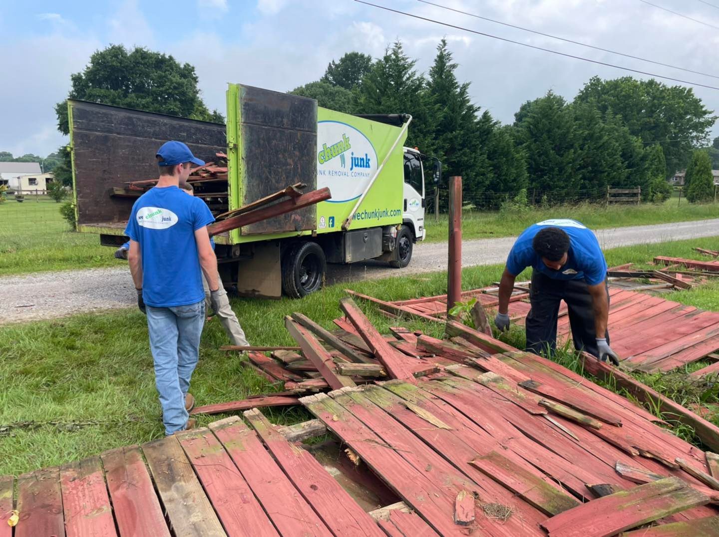 Two men are working on a pile of wood next to a truck.