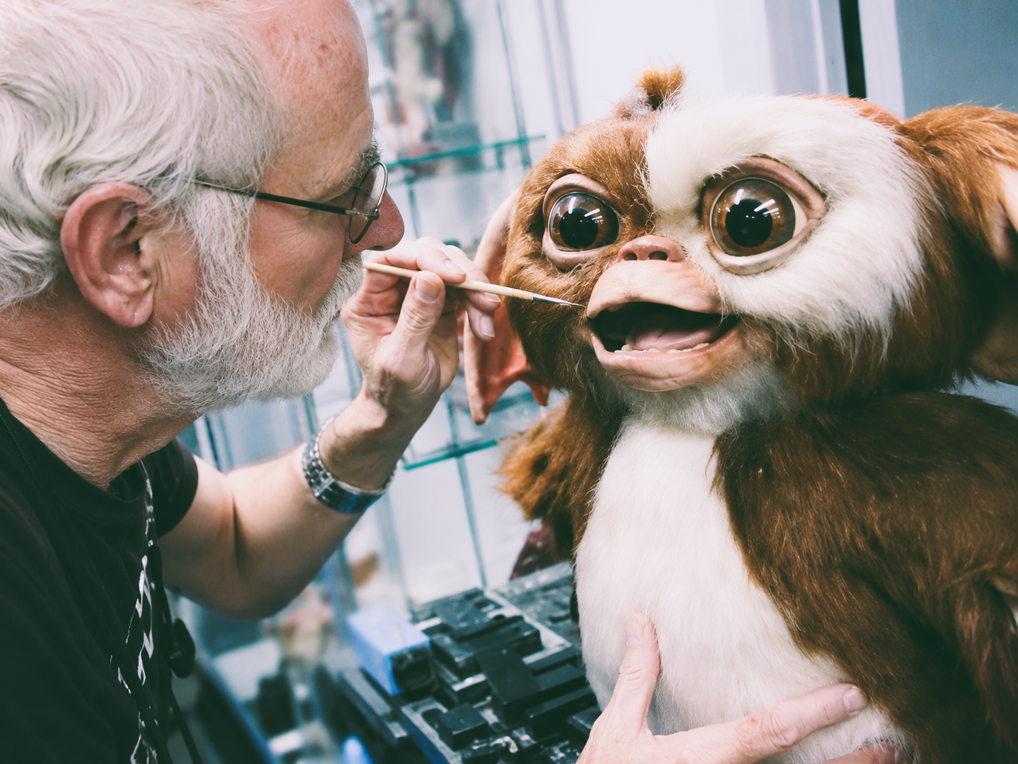Behind-the-scenes image of a Gizmo animatronic puppet being operated during the production of the Gremlins films.
