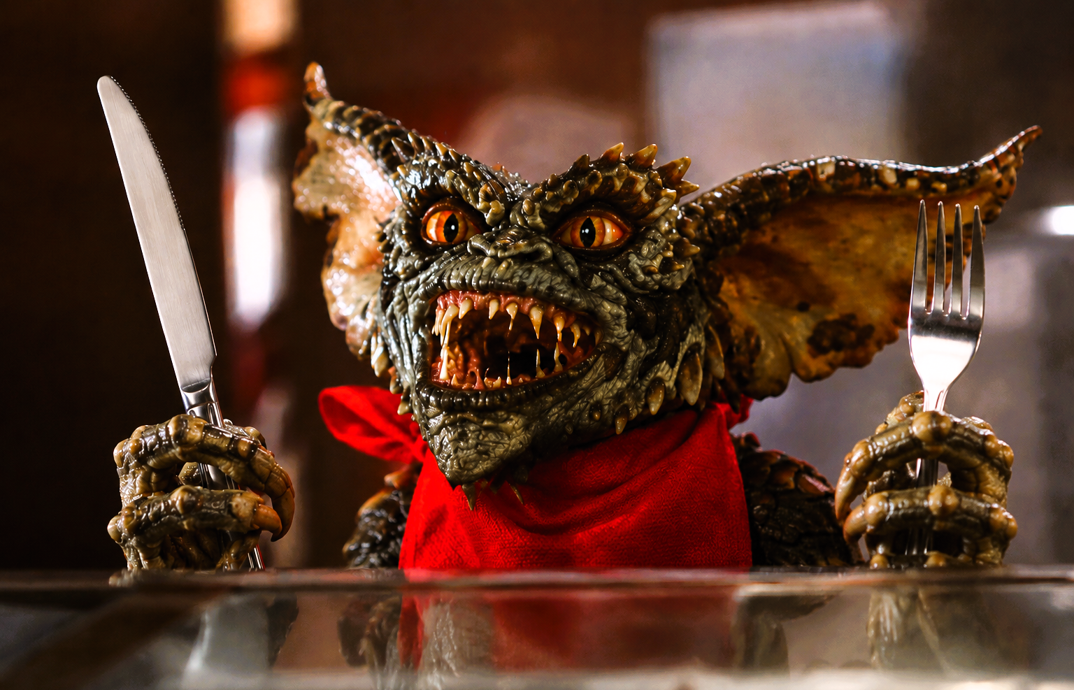 A classic Gremlin holding a knife and fork, representing excitement as Gremlins 3 prepares to return to cinemas.