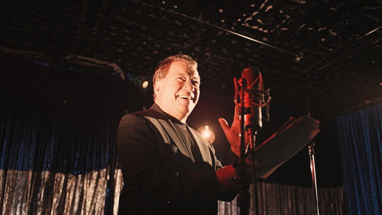 William Shatner speaking during a live performance, reflecting on his long career across music, theatre and entertainment.