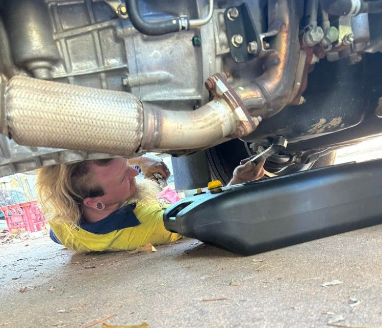 A Person Under a Car Changing the Oil — Mudpig Mechanical In Humpty Doo, NT