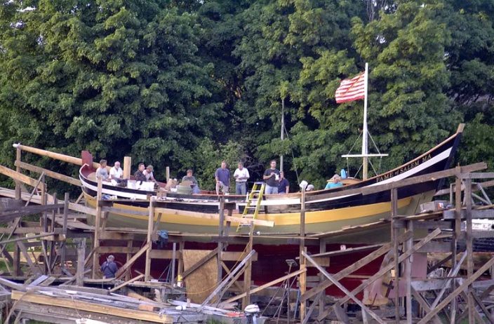 A group of people are standing on top of a boat being built