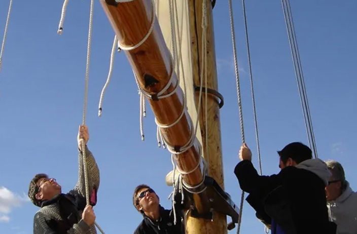 A group of people are raising sails on a boat tour in Salem