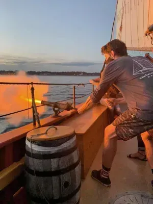 A group of people are standing on a boat looking at a fire.