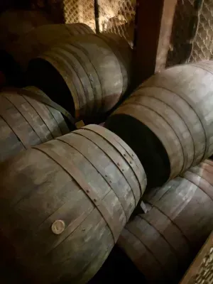 A bunch of wooden barrels are stacked on top of each other in a dark room.