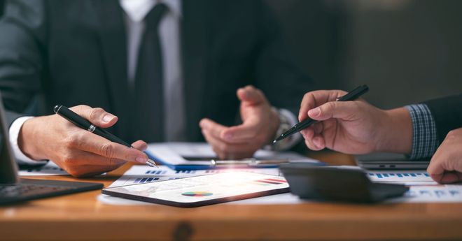 Business meeting with people reviewing documents and taking notes at a conference table
