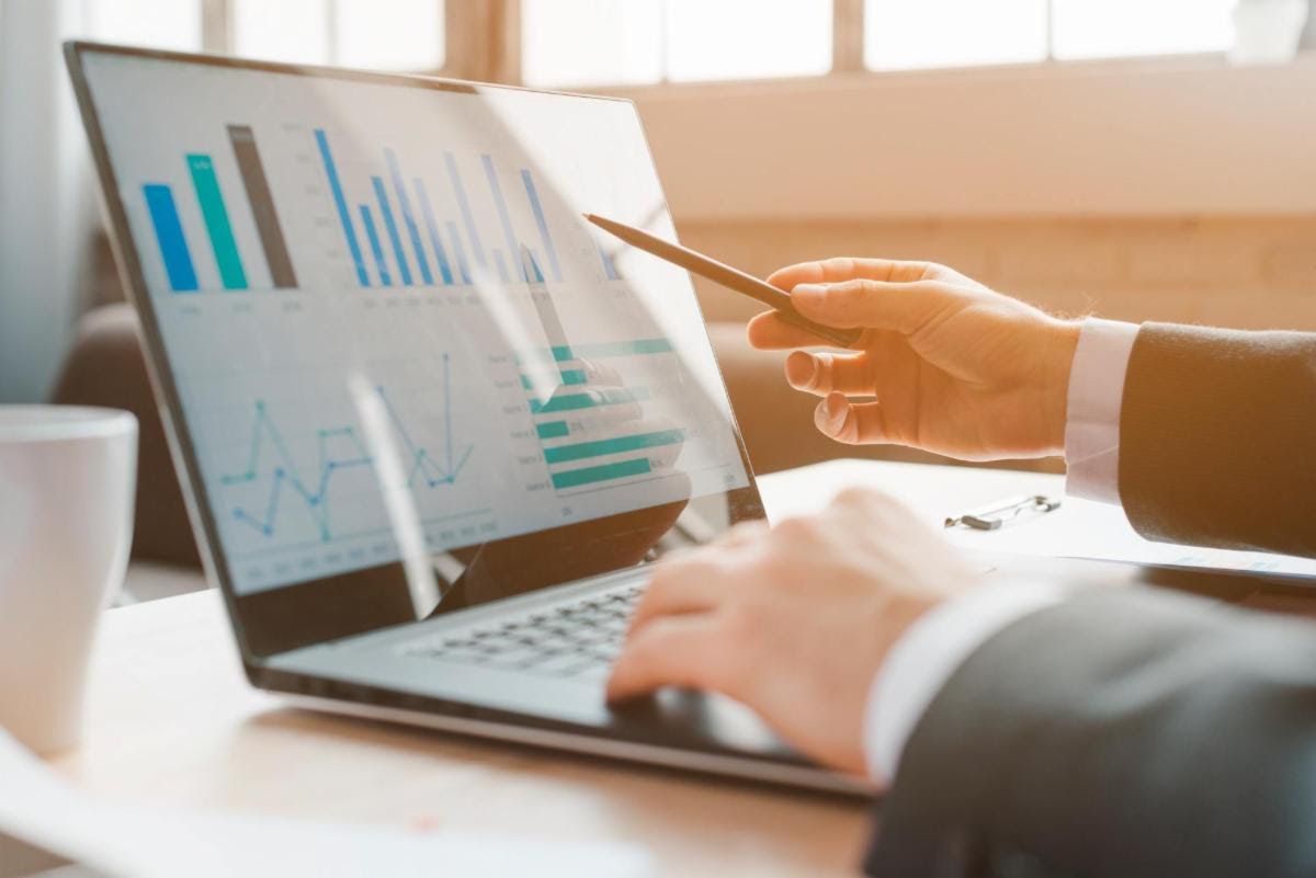 Business professional reviewing financial charts on a laptop, representing the Letter of Intent stag