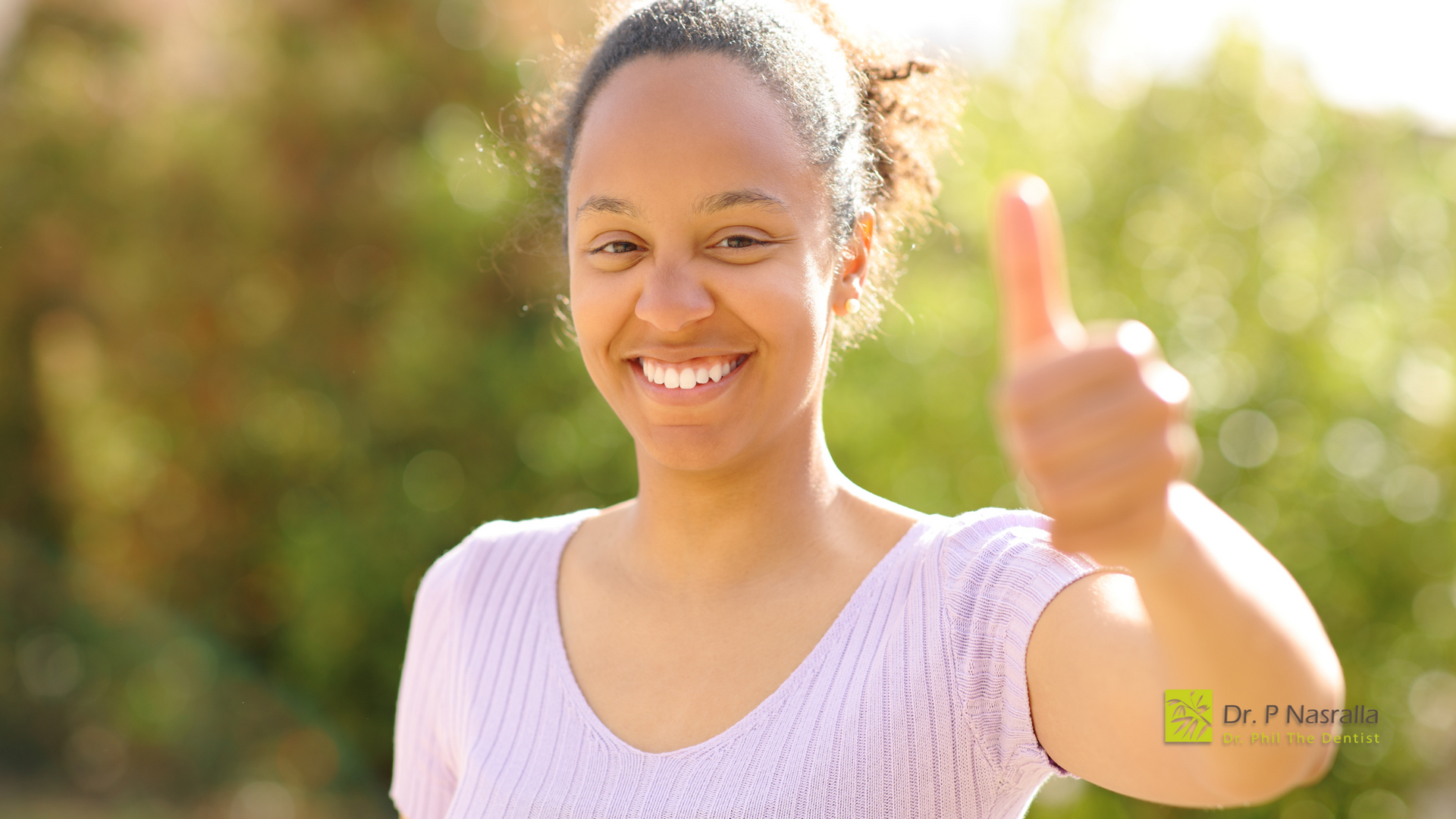 A woman is smiling and giving a thumbs up sign.