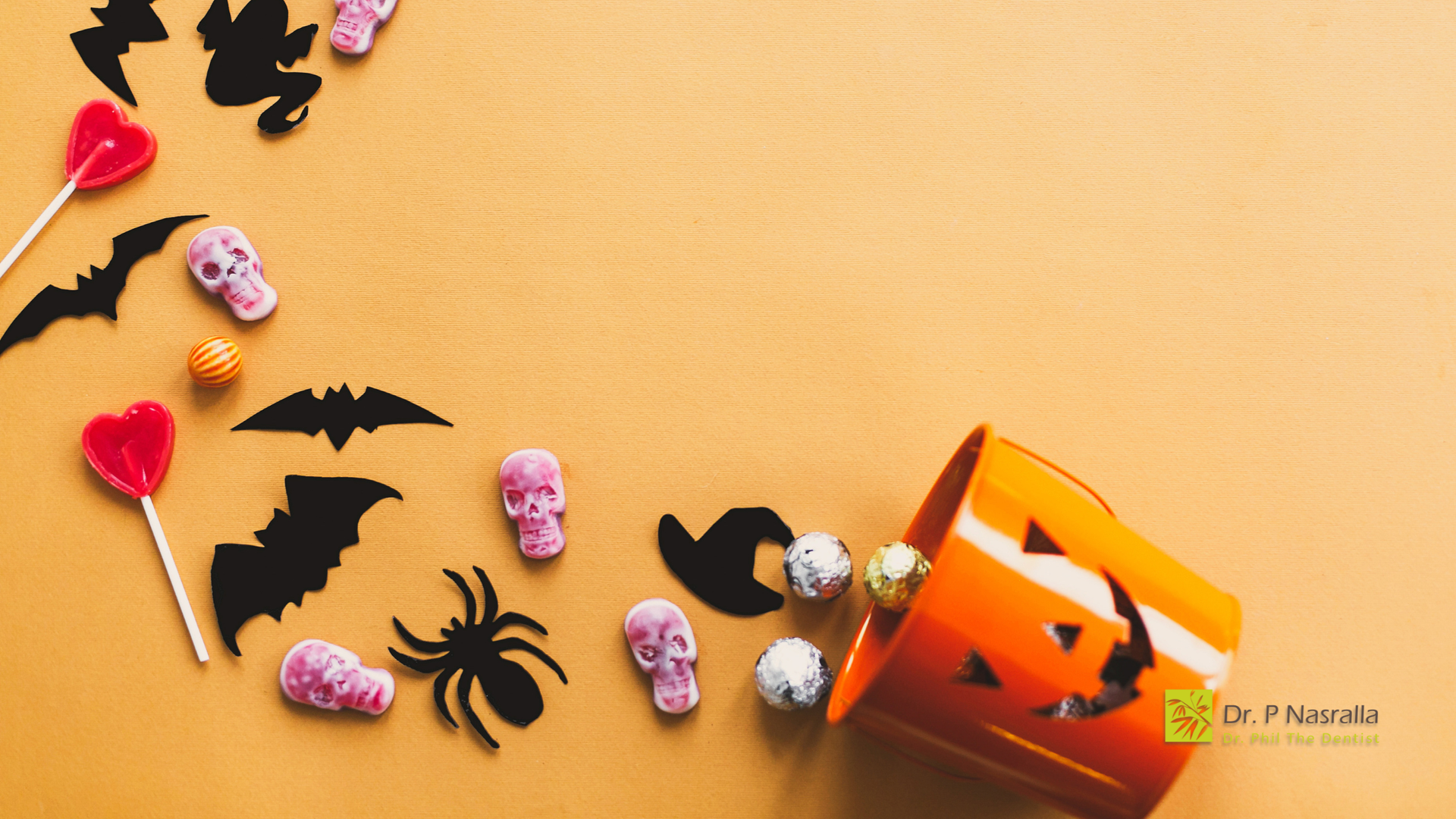 Halloween-themed orange background with scattered candy, bats, a spider, and an overturned jack-o'-lantern bucket.