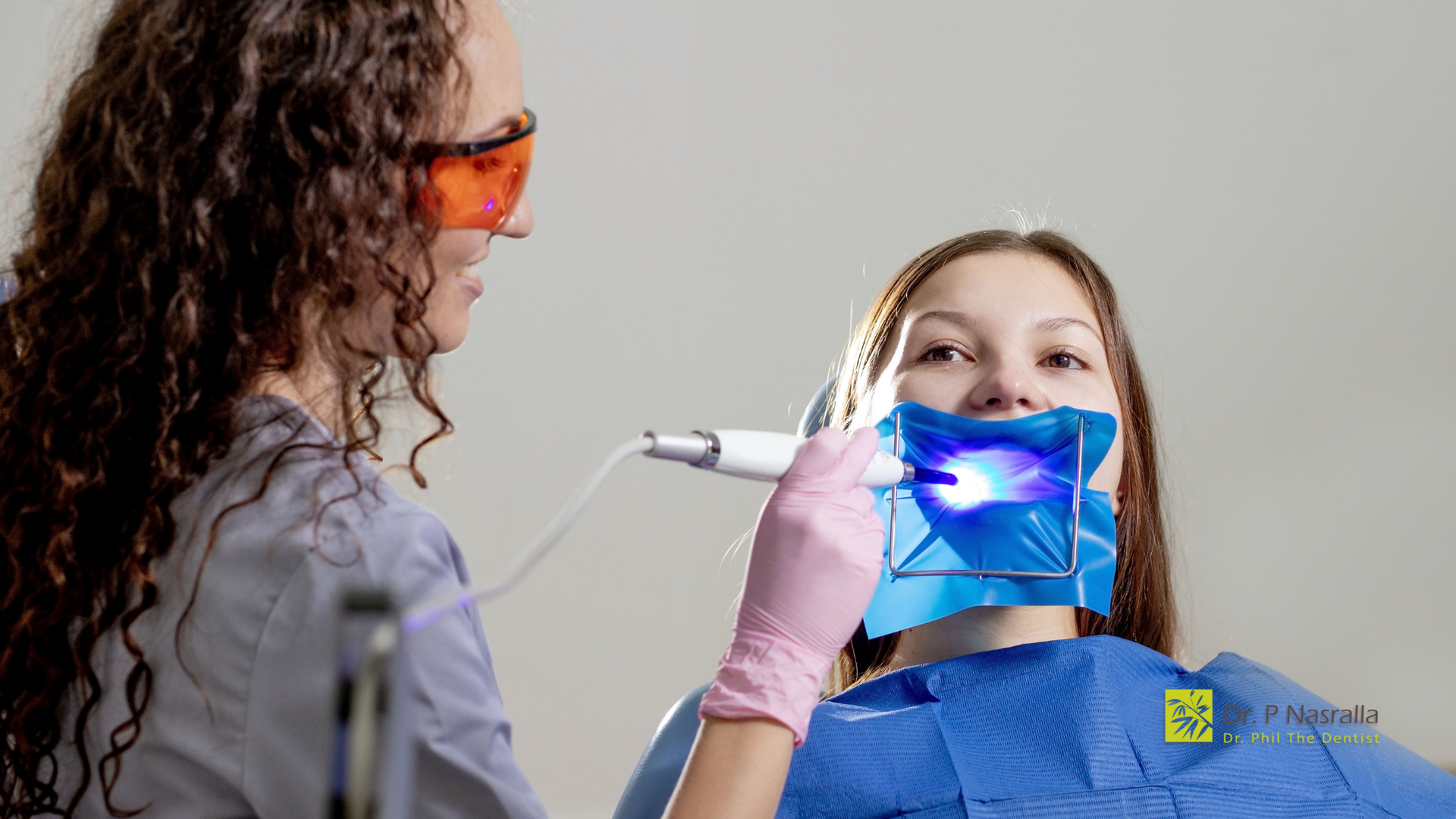 A woman is getting her teeth whitened by a dentist.