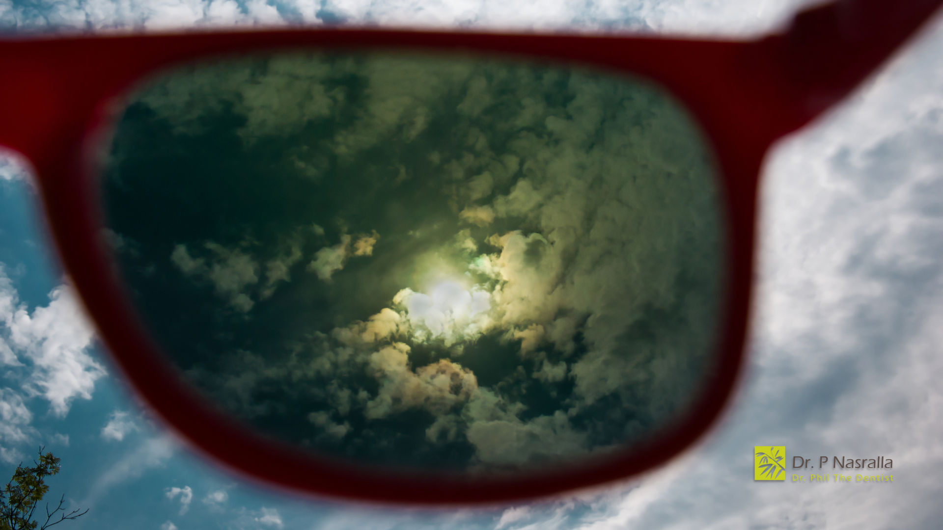 A pair of sunglasses with a cloudy sky reflected in them