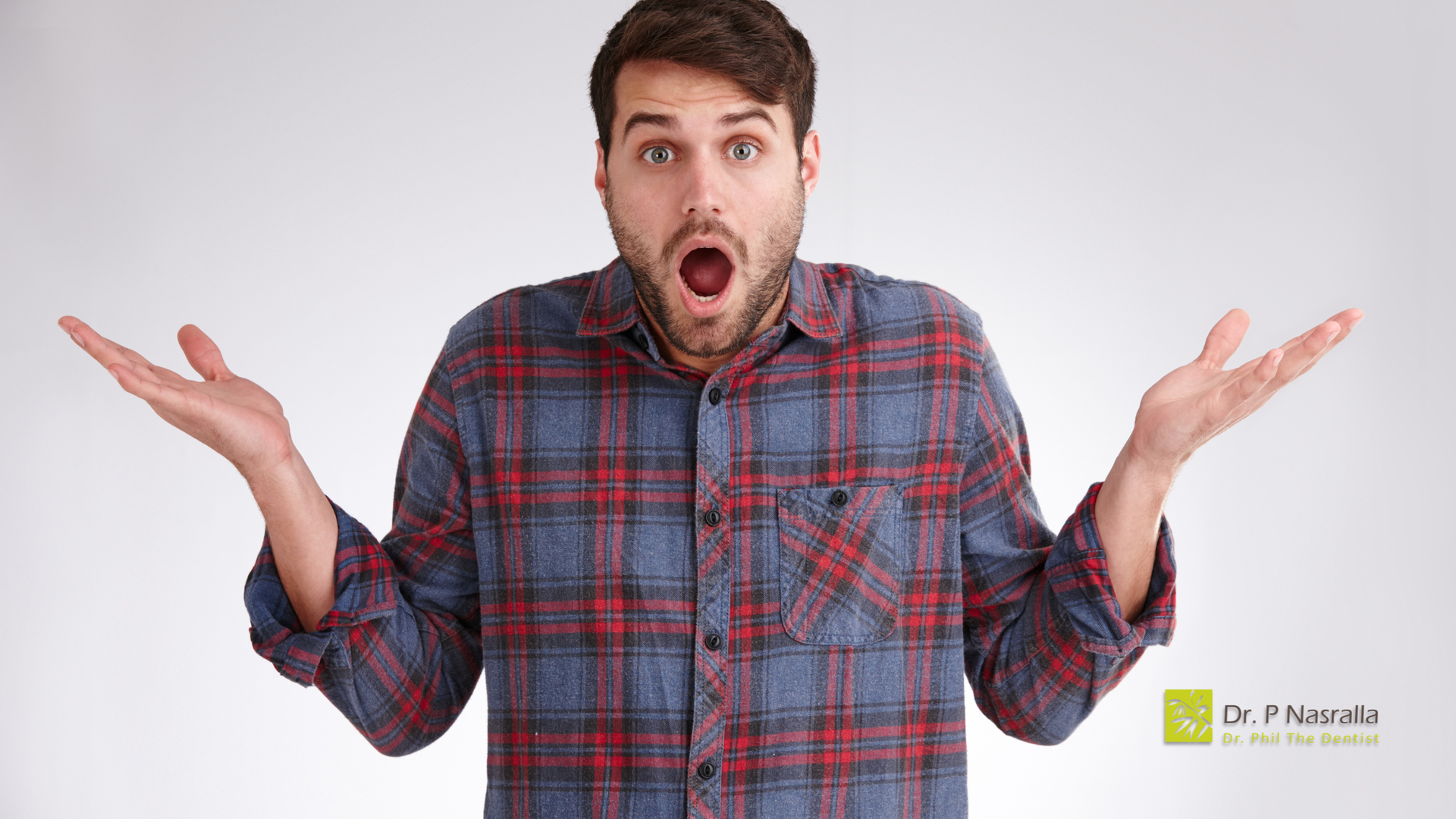 Man in plaid shirt with open mouth and outstretched arms, surprised expression.