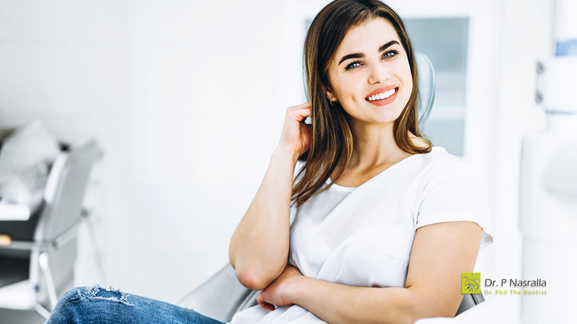 A woman is sitting in a chair with her arms crossed and smiling.