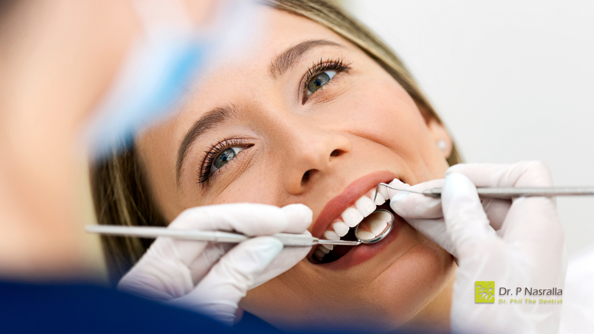 Woman at dental appointment, mouth open, dentist using tools.