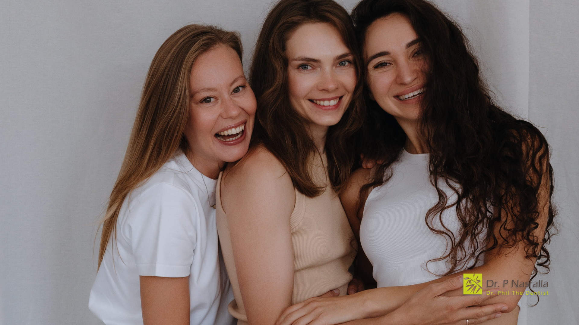 Three women are hugging each other and smiling for the camera.