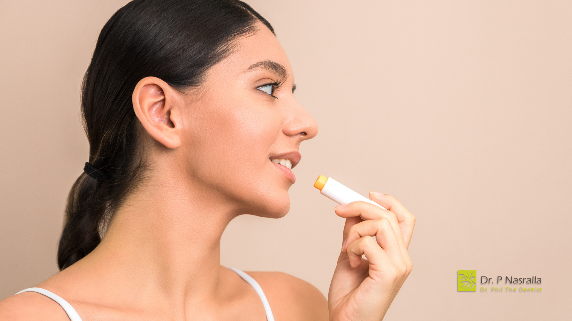 A woman is applying a lip balm to her lips.