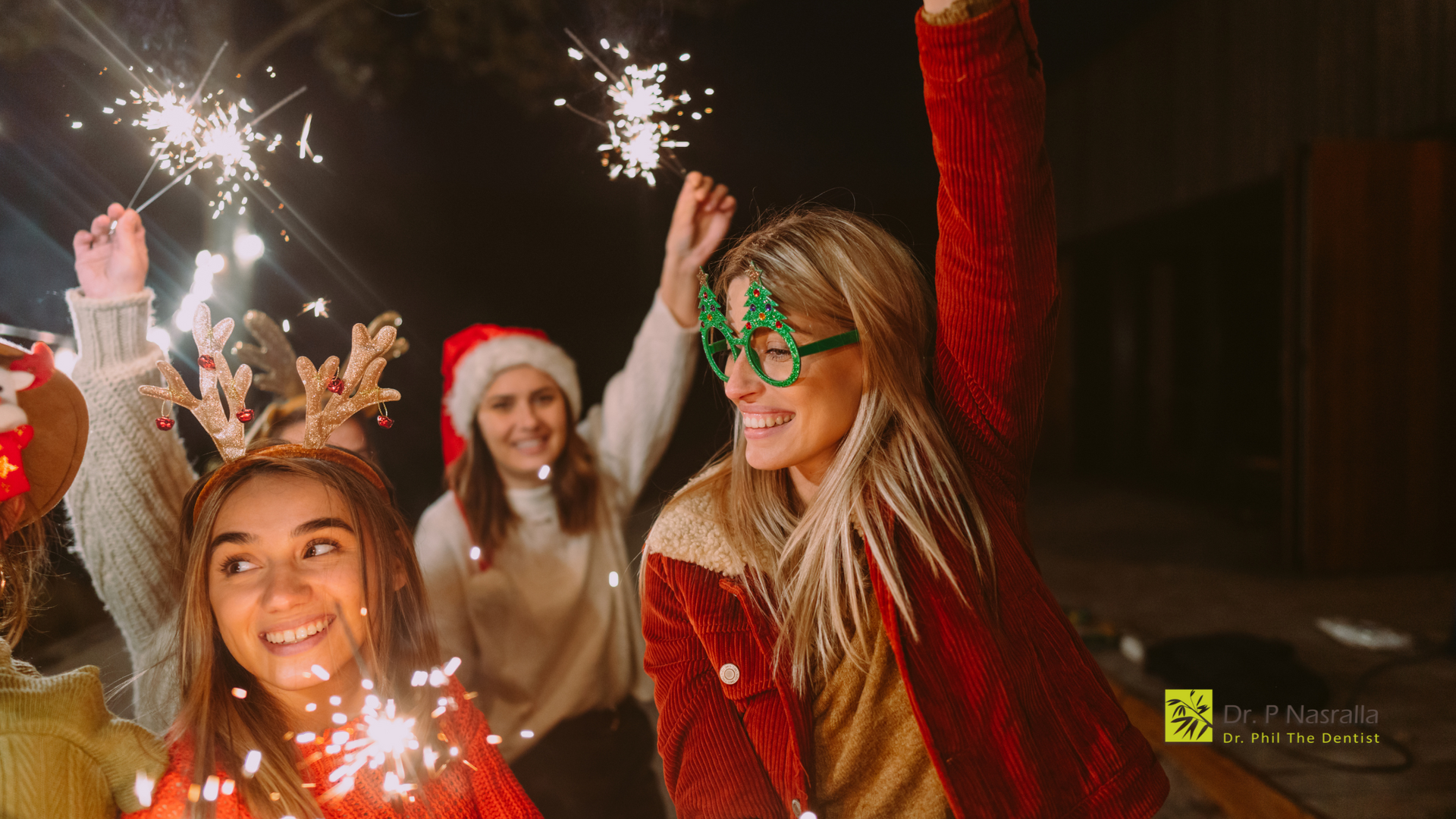 A group of women are holding sparklers at a christmas party.