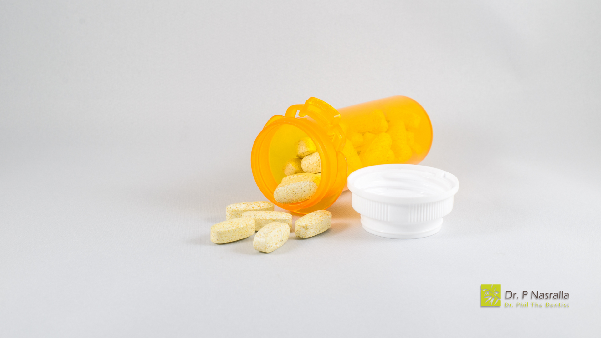A bottle of pills is spilling out of it on a table.
