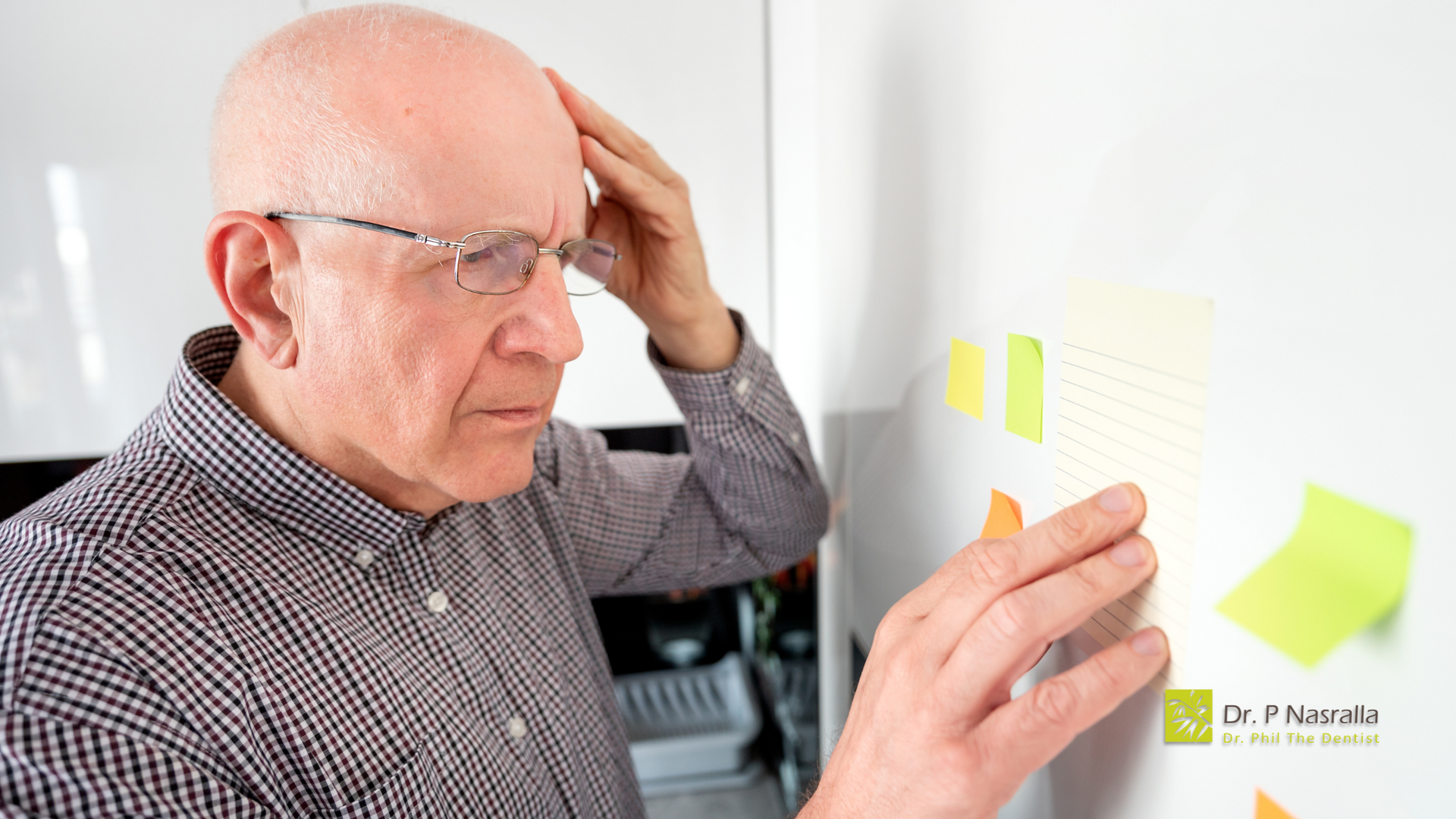 An elderly man is looking at sticky notes on a refrigerator door.