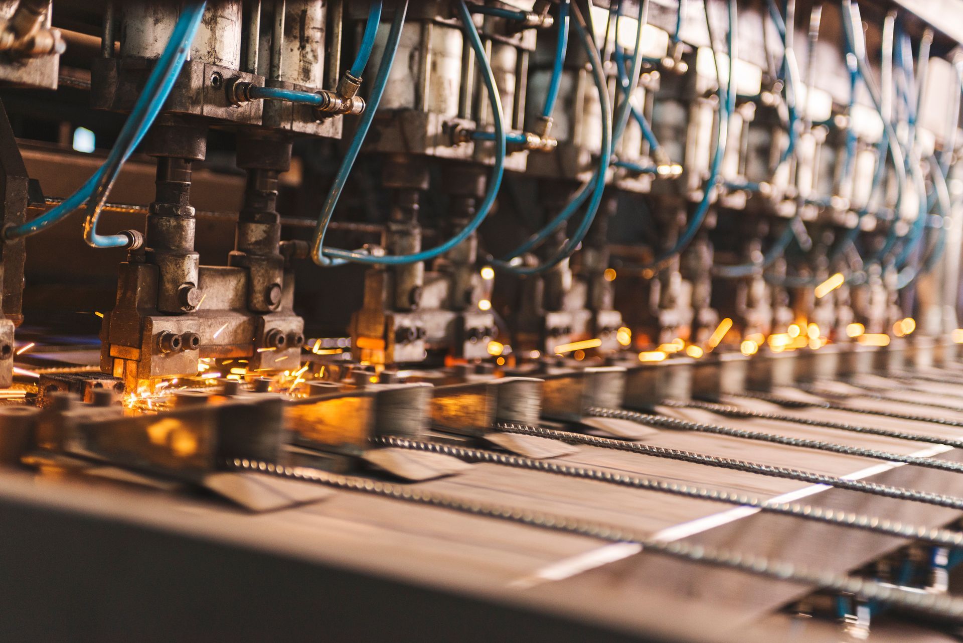 Saldatrice industriale in azione: scintille che volano quando unisce barre metalliche.