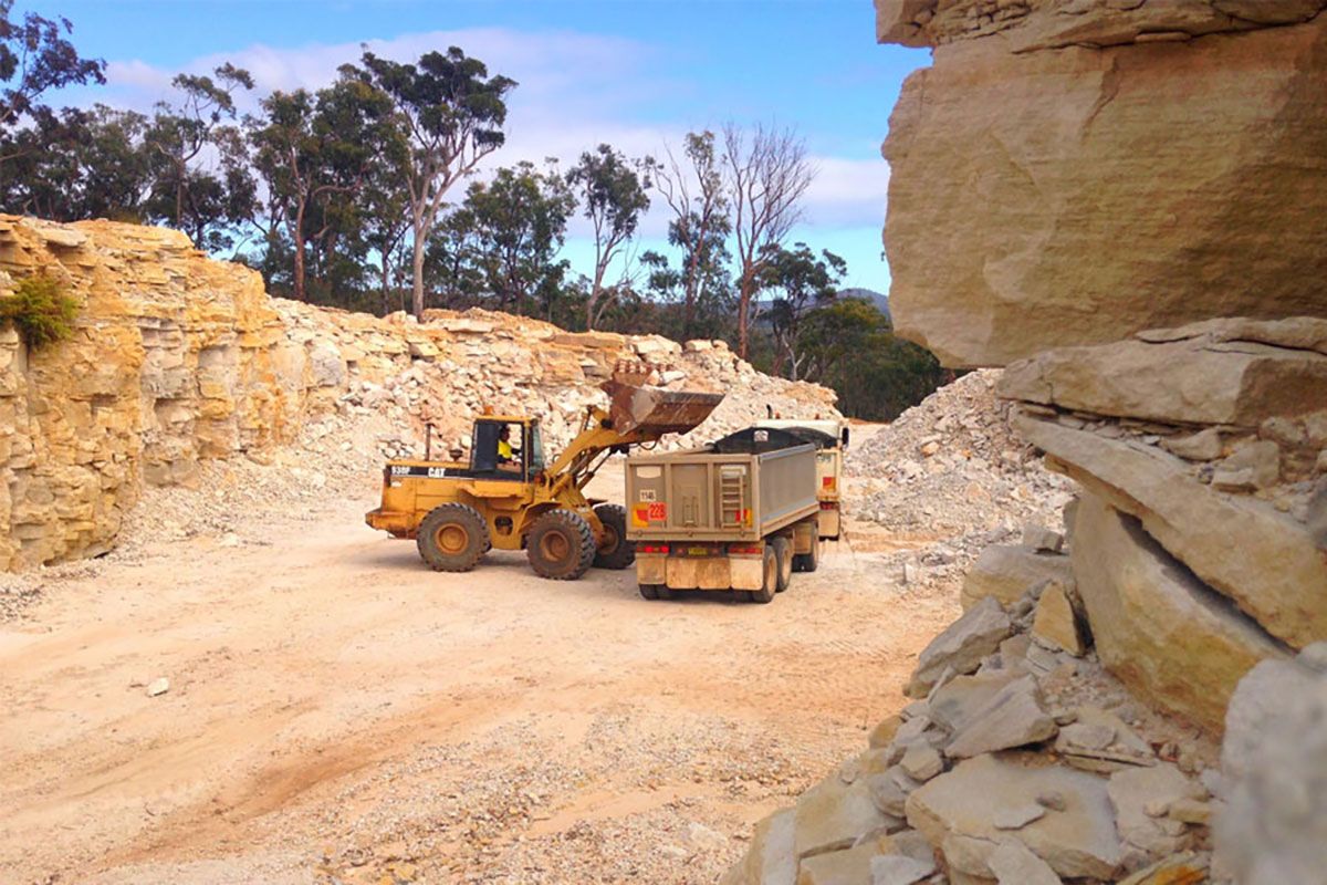 A bulldozer is loading a truck in a quarry.