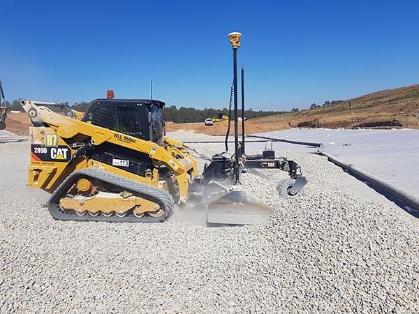 A yellow cat bulldozer is moving gravel on a construction site.