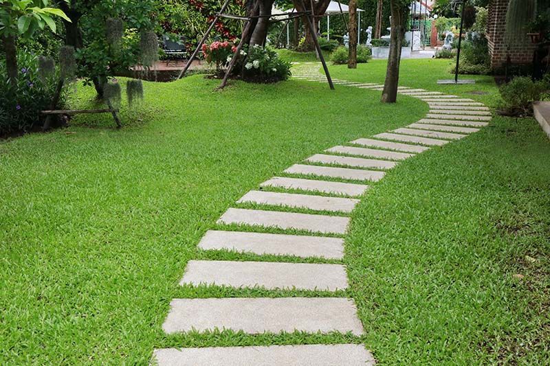 Une allée en pierre traversant un jardin verdoyant.