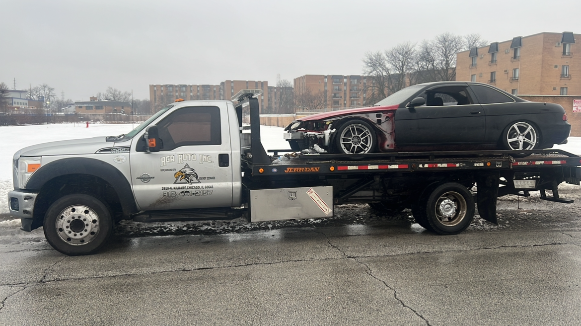 A tow truck is towing a car on the side of the road.