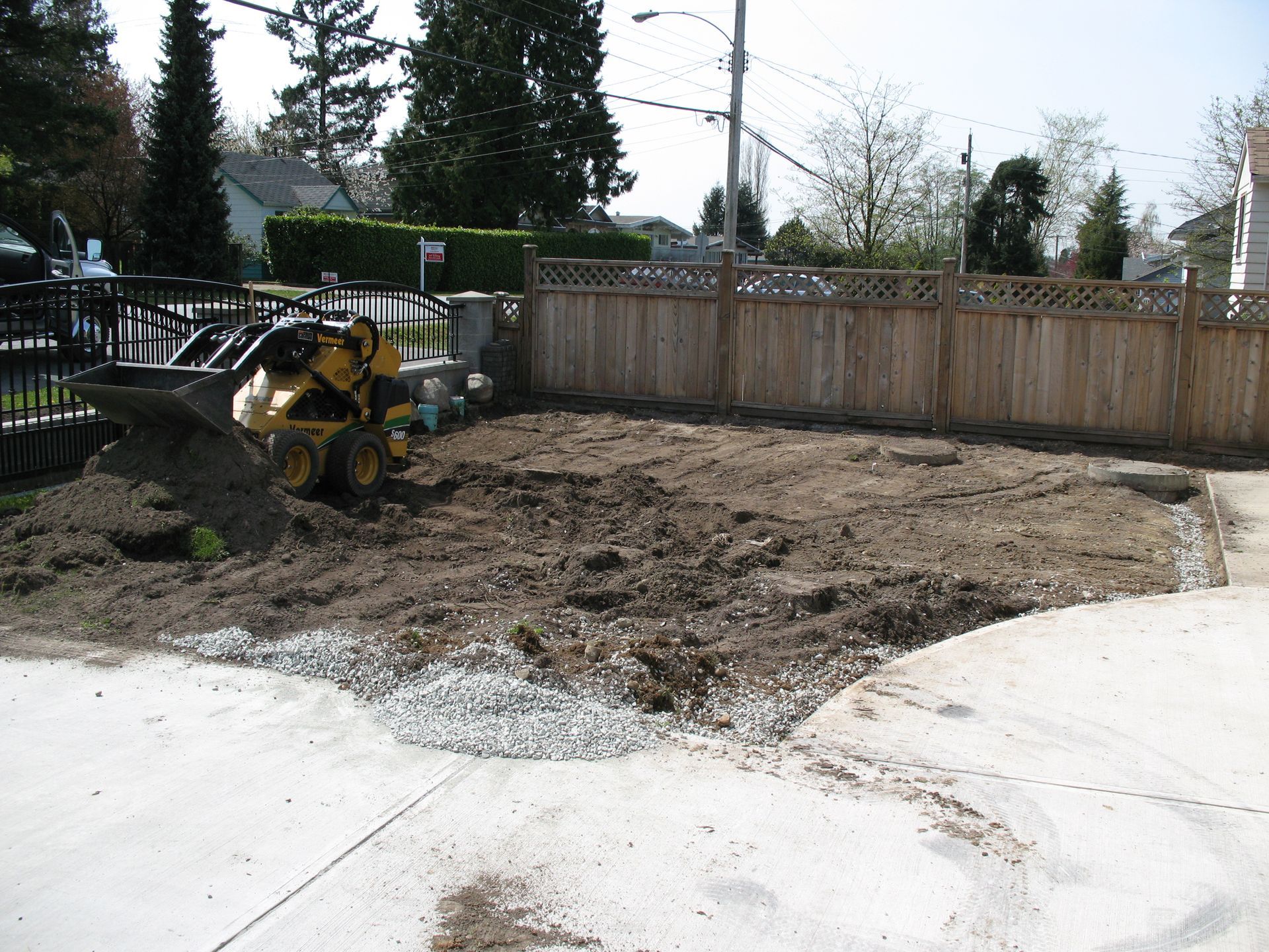 Excavator in back yard clearing land for landscape design isntallations