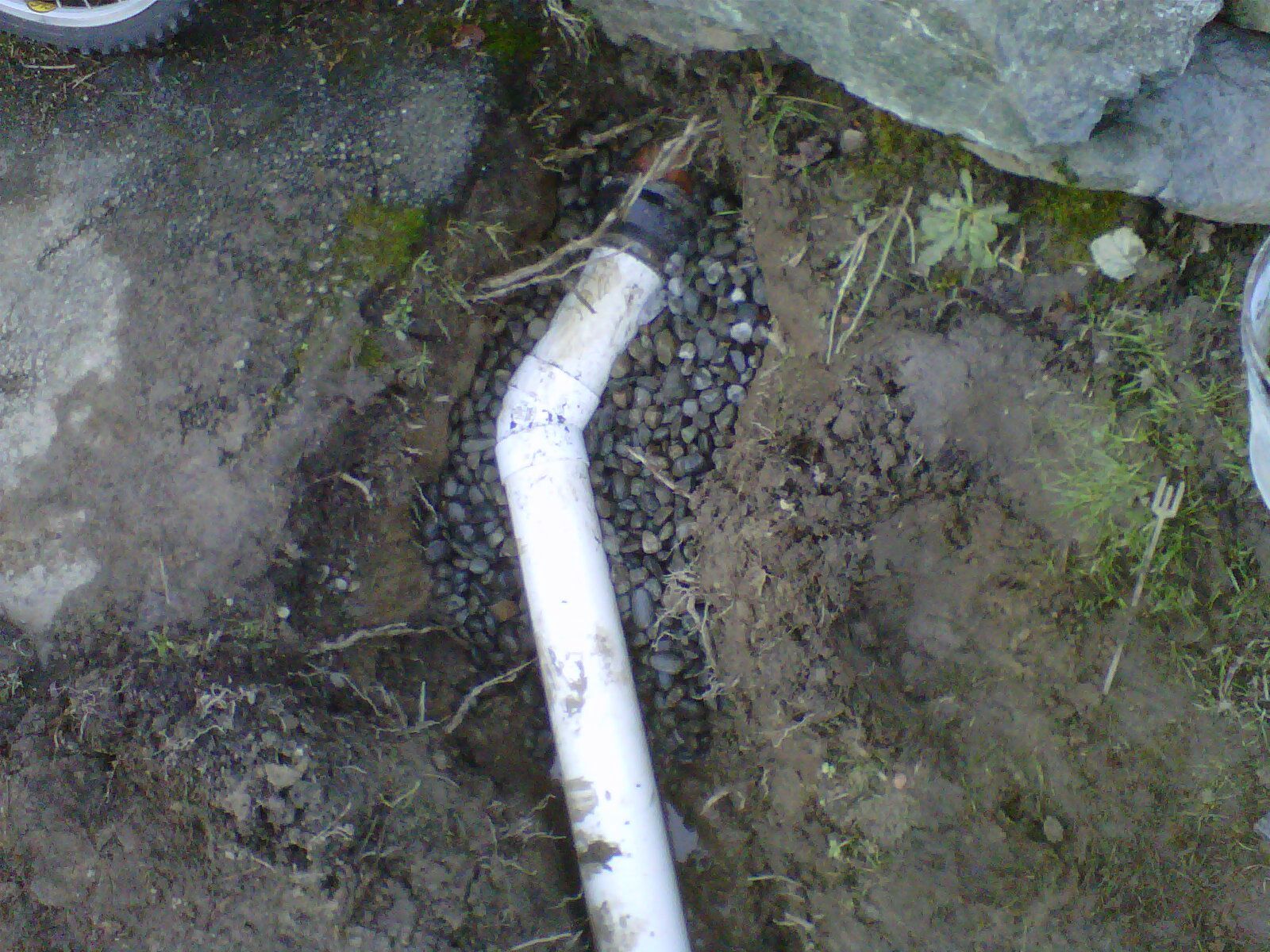 A trench revealing a PVC drain pipe