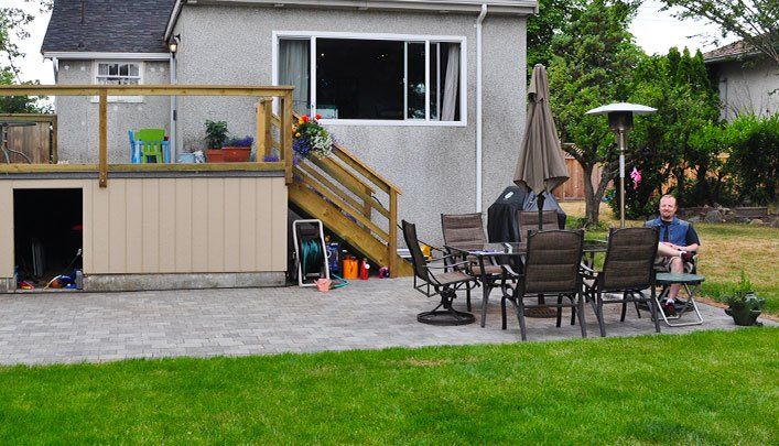 Another view of Ross Dunn smiling at the camera from his patio chair after getting new drainage services completed