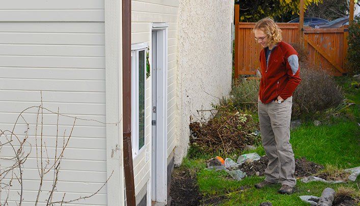 RainTek Drainage customer in Victoria BC looking down at a problem with his drainage system