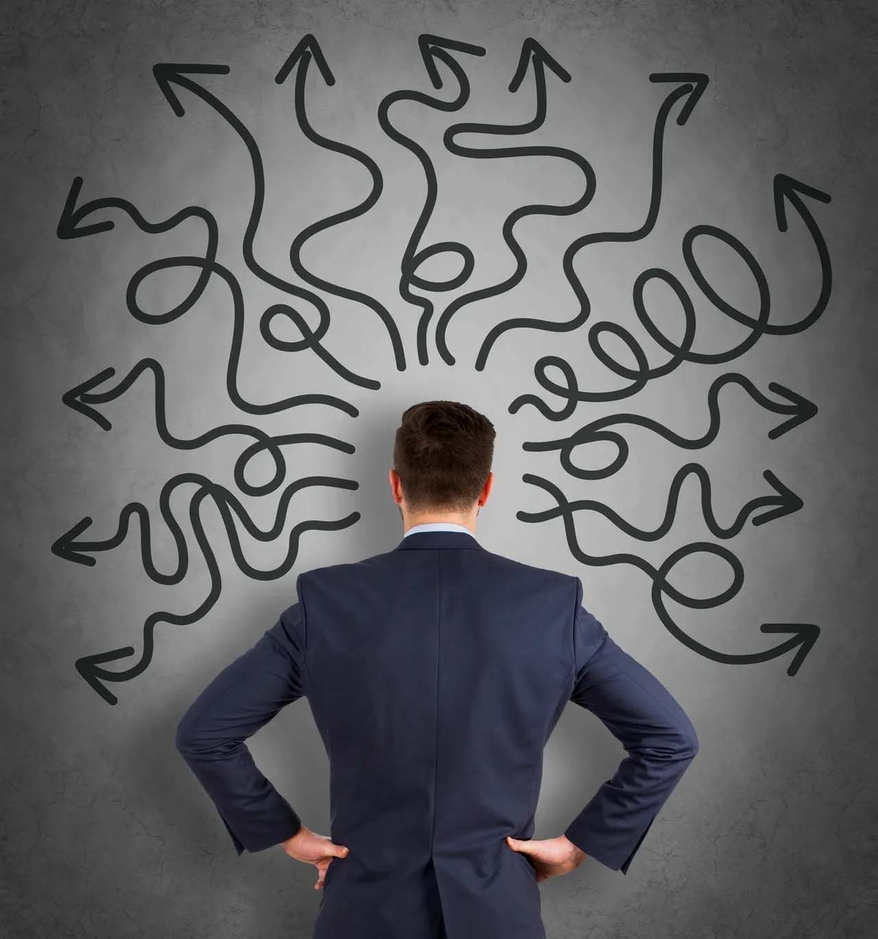 a man in a suit stands in front of a drawing of arrows pointing in different directions