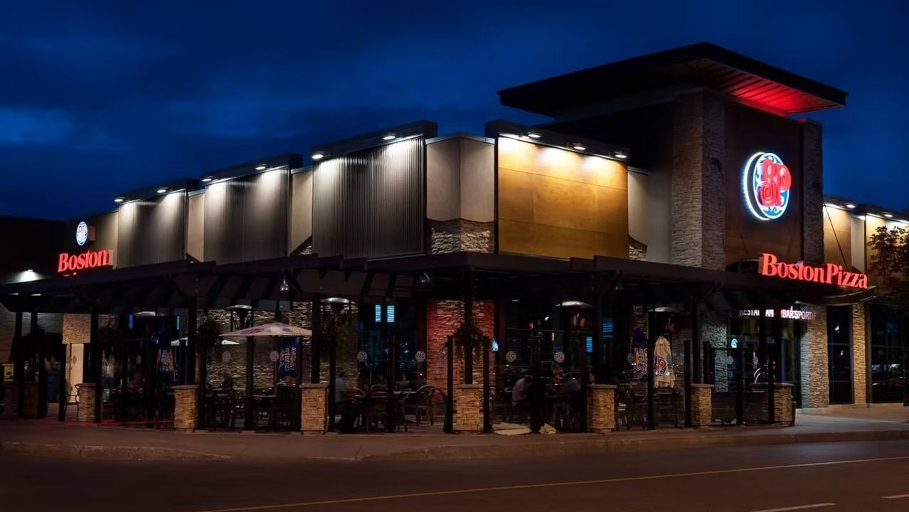 Boston Pizza restaurant exterior at night with neon sign.