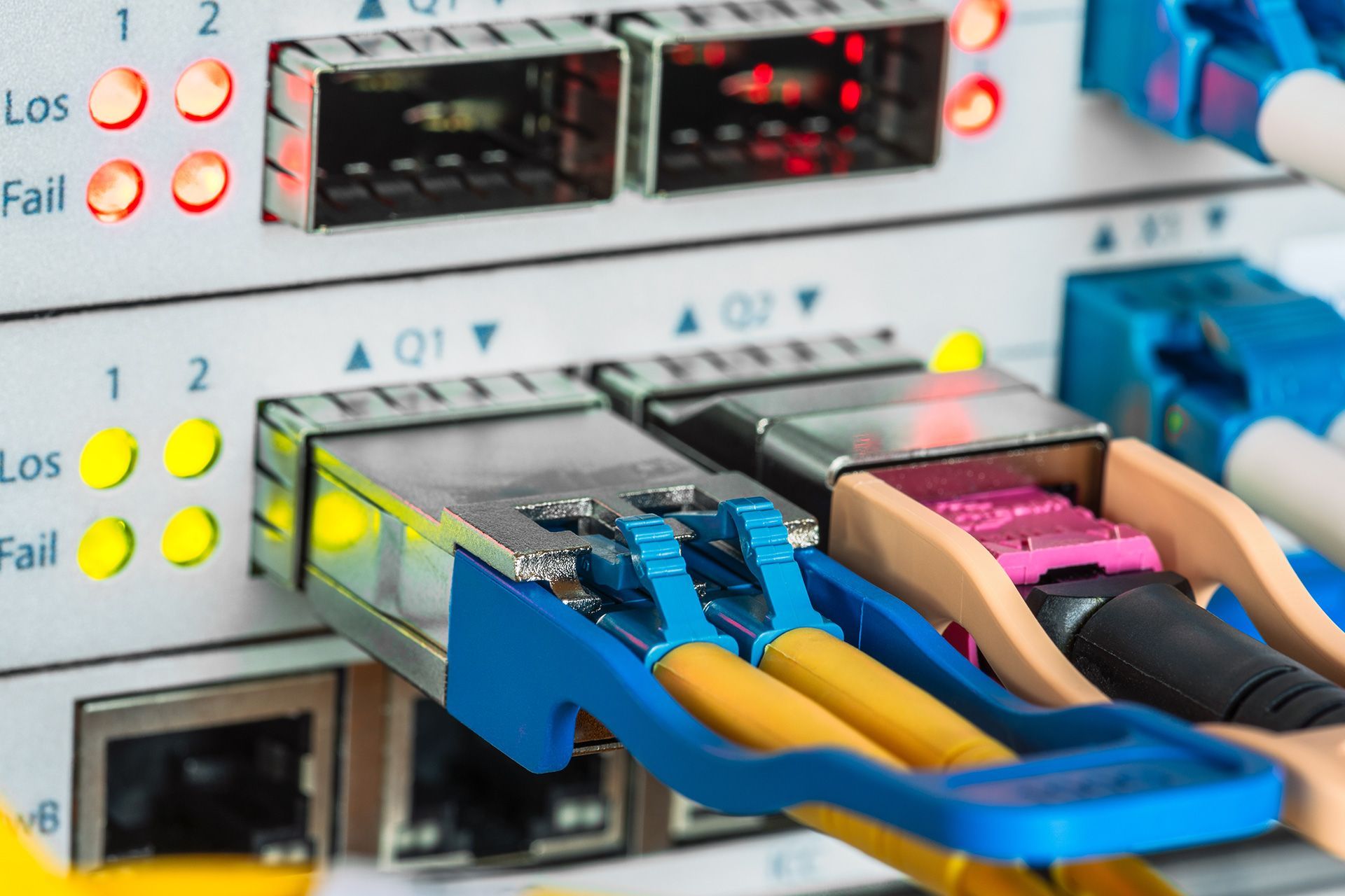 Close-up of network switch with fiber optic cables and indicator lights.