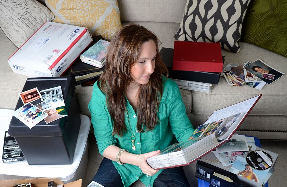 A woman is sitting on the floor looking at a photo album.