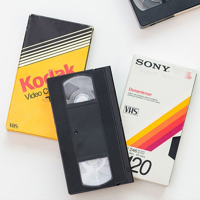A vhs tape sits next to a kodak tape and a sony tape