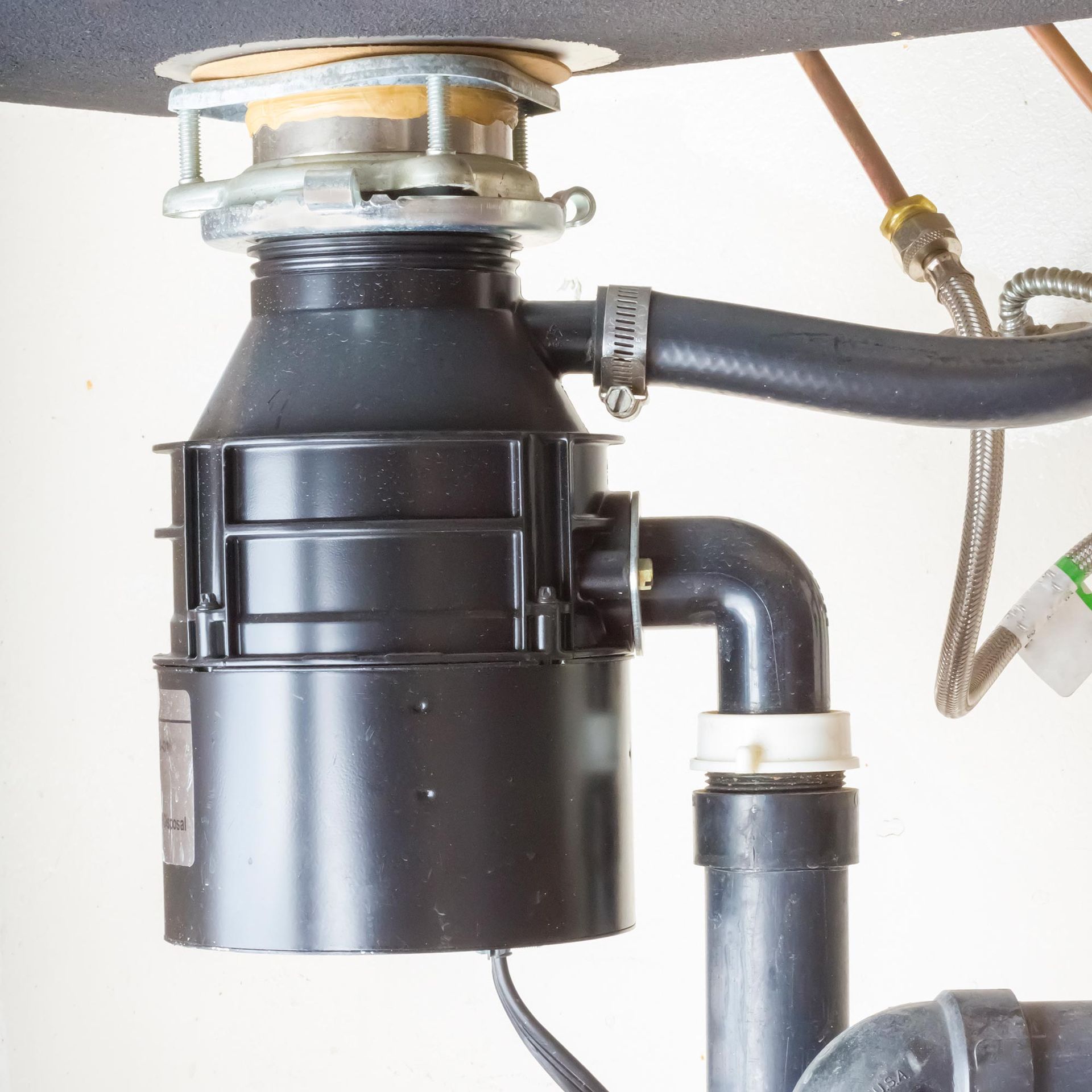 A black garbage disposal is attached to a sink