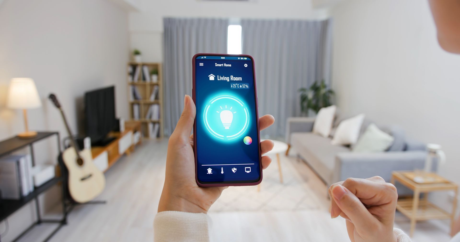 Person holding a smartphone with a glowing app in a bright living room with a guitar and sofa
