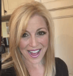 A woman is smiling and taking a selfie in a kitchen.