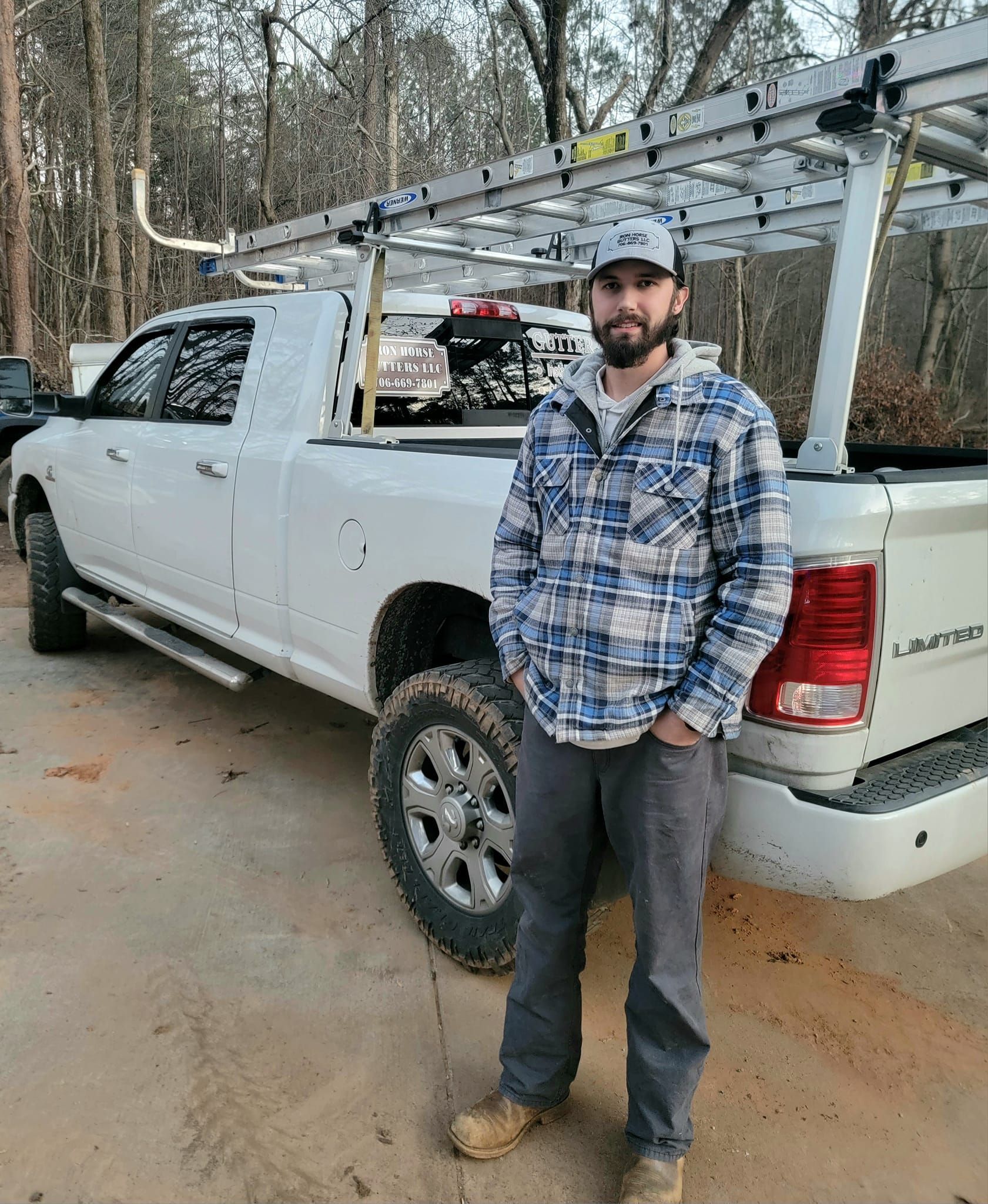 A man in a plaid shirt is standing in front of a white truck.