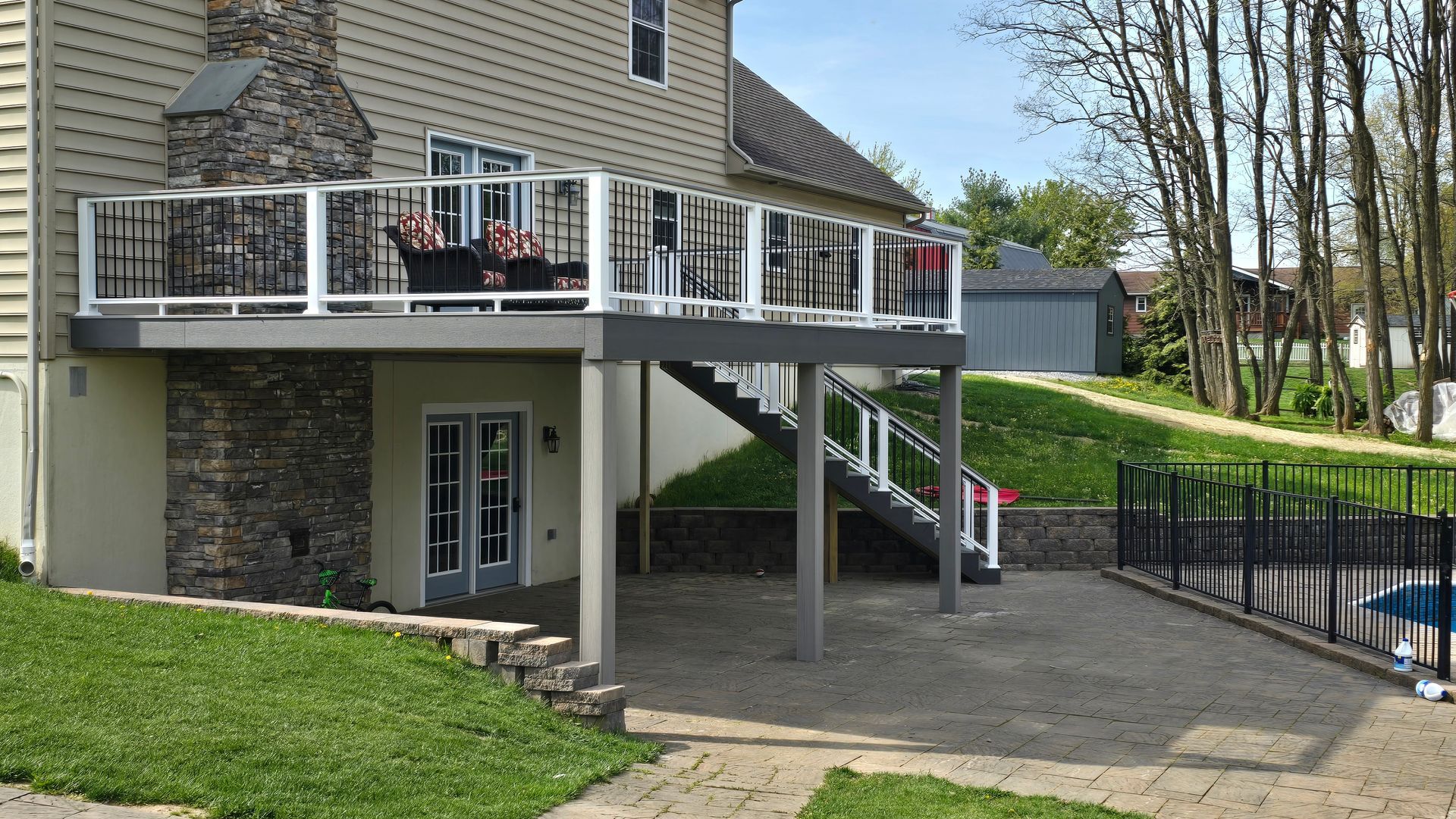 A large wooden deck with a white railing in front of a house.
