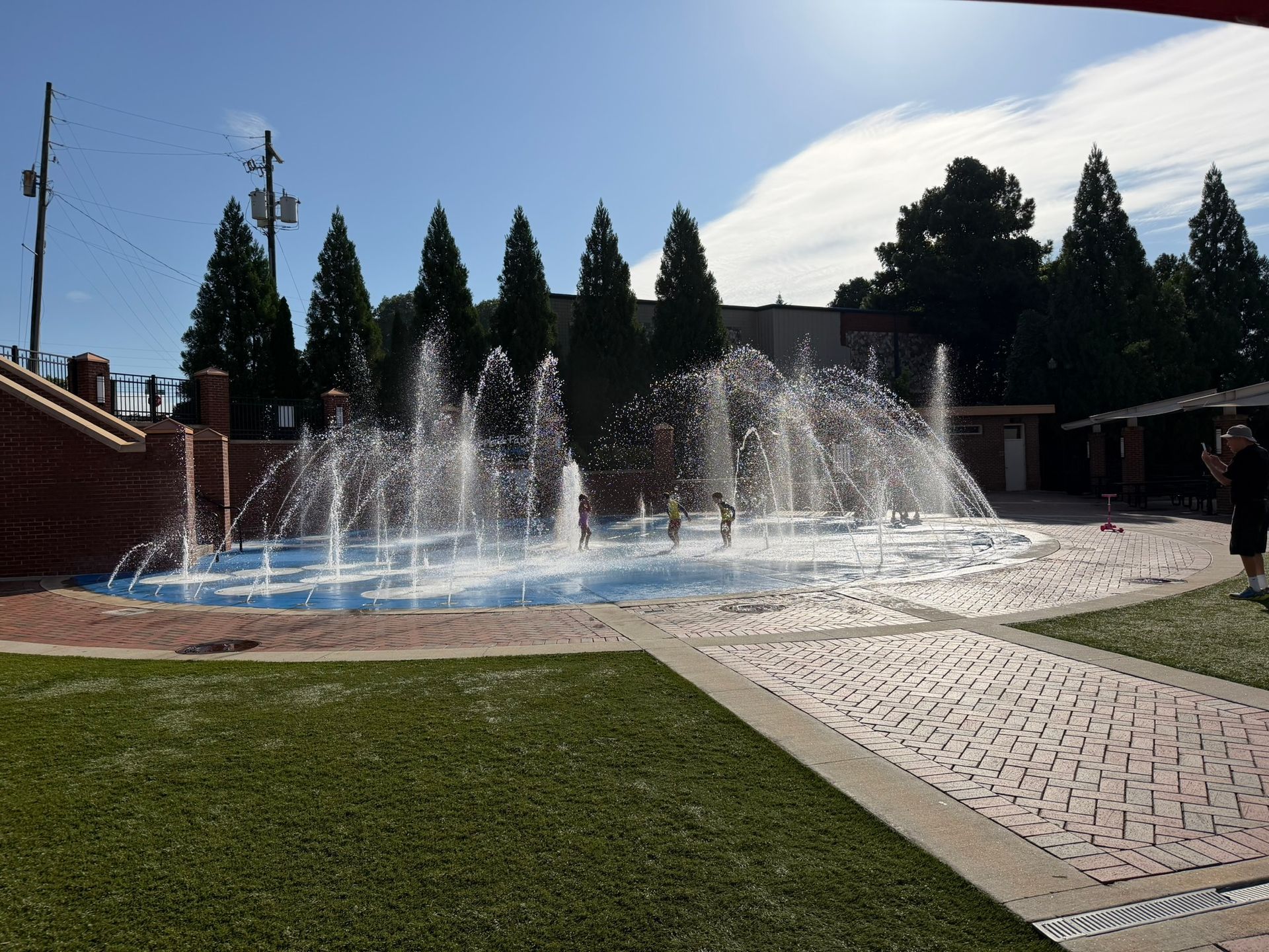 Children play in the fountains at Sugar Hill Splash Park in downtown Sugar Hill, Georgia, cooling off after the Splash Dash 5K.